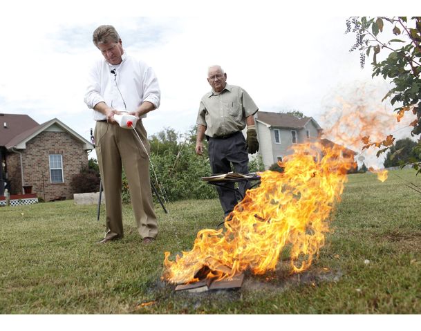 Pastor Bob Old sprays lighter fluid onto burning copies of the Koran and The Book of Mohammed while Pastor Danny Allen watches at Old's home in Springfield, Tennessee {allvoices}